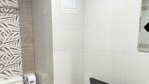 Un baño con inodoro, lavamanos y zona de ducha.
