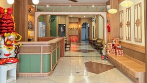 A hotel lobby with a reception desk, seating area, and a view of the dining area. - Jacky Chan Hotel (Betong)