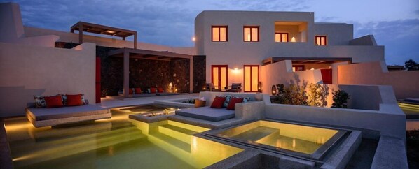 Um edifício moderno com piscina, área de estar ao ar livre e um muro de pedra.