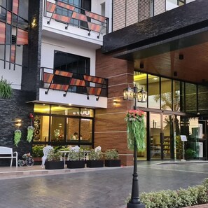 Un hotel con facciata moderna, area salotto esterna e ingresso ben illuminato.