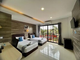Habitación de hotel con dos camas, un escritorio, un televisor y un ventanal con vistas.