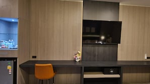 A modern kitchen with a built-in TV, a small refrigerator, and a wooden cabinet.