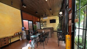 A restaurant interior with tables, chairs, a coffee machine, and a brick wall.