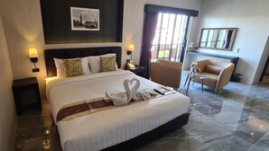 Una camera d'albergo con un letto grande, una sedia, un tavolino e un quadro raffigurante un ponte appeso al muro.