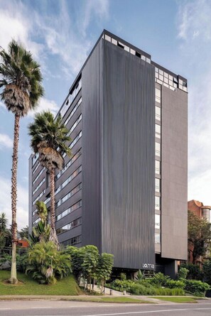 A modern building with a vertical facade, multiple windows, and a sign reading 'LOMA'. - Versus Hotel (Medellín)