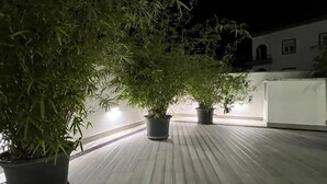 A rooftop terrace with potted plants and a building in the background. - Hotel Buzio (Sines)