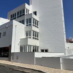A modern building with a white facade, multiple windows, and a flat roof. - Hotel Buzio (Sines)