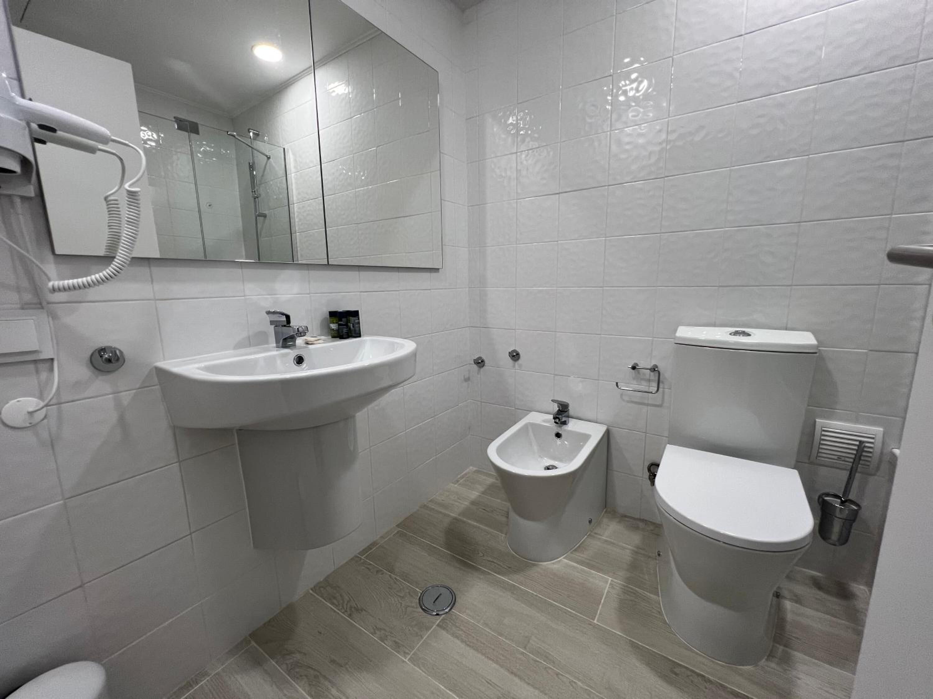 A modern bathroom with a sink, bidet, and toilet.