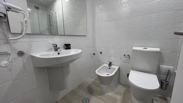 A modern bathroom with a sink, bidet, and toilet.