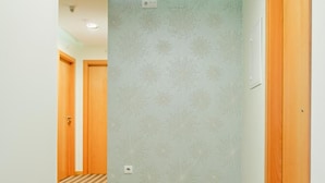 A hallway with patterned wallpaper, wooden doors, and a striped carpet. - Hotel D. Dinis (Leiria)