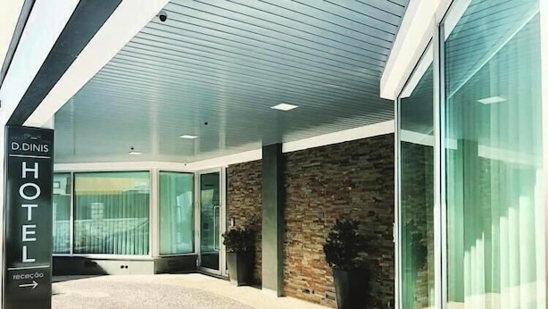A hotel entrance with a modern design, featuring a stone facade, large glass doors, and a sign indicating the hotel name. - Hotel D. Dinis (Leiria)