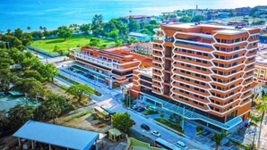 A multi-story building with a distinctive zigzag pattern on the facade, surrounded by greenery and a clear blue sky. - The Aurora Subic Hotel Managed by HII (Olongapo)