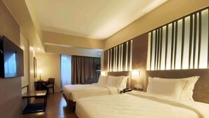 A hotel room with two beds, a desk, a chair, and a TV. - The Aurora Subic Hotel Managed by HII (Olongapo)