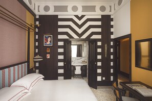 A hotel room with a bed, a bathroom with a mirror and sink, and a TV on the wall. - Palazzo Roma (Rome)