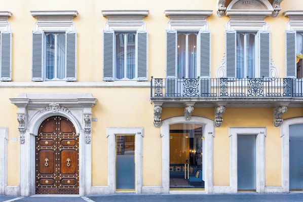 A building with a large wooden door, multiple windows with shutters, and a balcony with ornate metal railings. - Palazzo Roma (Rome)