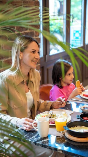 A woman and a child dining at a table with a variety of food items and drinks. - Nex Hotel Istanbul City Center (Istanbul)
