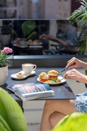 A person dining outdoors with a table, a cup, a plate with food, and a book. - Nex Hotel Istanbul City Center (Istanbul)