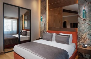 A hotel room with a large bed, a mirror, a wooden headboard, and a stone-patterned wall. - Nex Hotel Istanbul City Center (Istanbul)