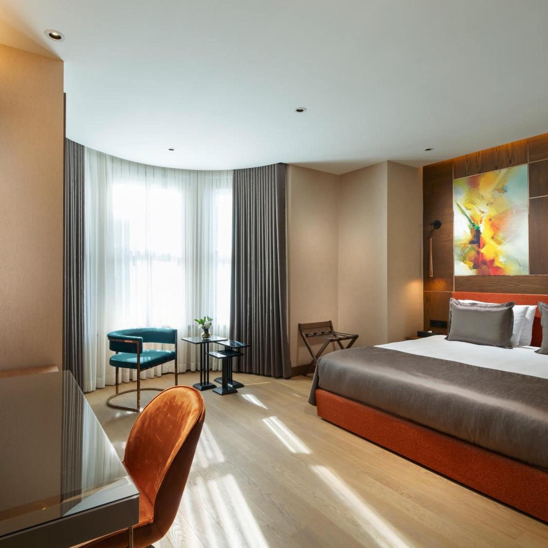 Une chambre d’hôtel avec un grand lit, un bureau, une chaise et une vue sur la ville par la fenêtre.