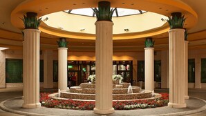 A hotel lobby with a central fountain, large columns, and a skylight. - Park Casino And Hotel (Nova Gorica)