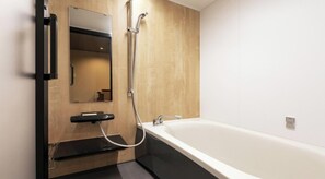 Un baño moderno con una bañera independiente, un cabezal de ducha manual y un espejo sobre un lavabo negro.