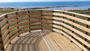 A wooden deck with a curved railing overlooking a beach. - Golf View Hotel & Macintosh Restaurant (Lossiemouth)