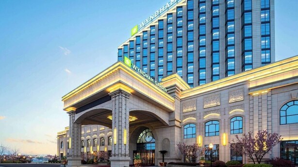 Un hotel de varios pisos con una entrada destacada que presenta un gran arco y una fachada bien iluminada.