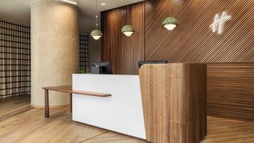 A reception area with a wooden reception desk, a white counter, and a modern design with vertical wooden slats and hanging pendant lights.