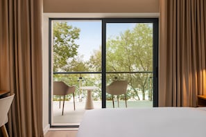 A hotel room with a large sliding glass door leading to an outdoor seating area with two chairs and a table. - Holiday Inn Beja (Beja)