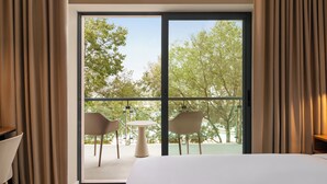 A hotel room with a large sliding glass door leading to an outdoor balcony with two chairs and a small table. - Holiday Inn Beja (Beja)