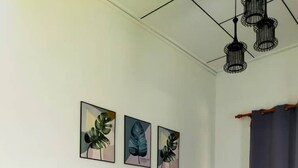 A modern living room with a dark blue leather sofa, three framed botanical prints on the wall, and a patterned floor. - Homestay Selesa KBB 2 Guest House (Kuala Terengganu)