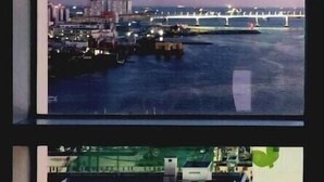A view through a window of a building with a marina and a bridge in the background. - The Bayment Residence (Busan)