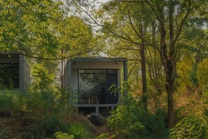 A modern house with a balcony, surrounded by dense greenery and trees. - Inap Luxury Cabin Kintamani (Kintamani)