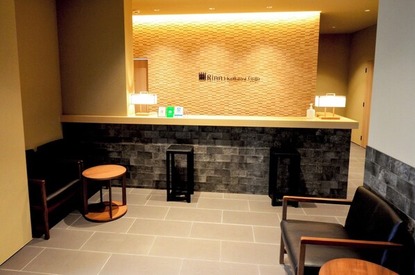 A reception area with a wooden wall, a reception desk, two chairs, and a small round table.