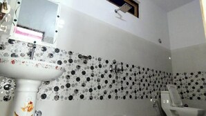 Une salle de bain avec un lavabo blanc, un miroir, des toilettes et une petite fenêtre.