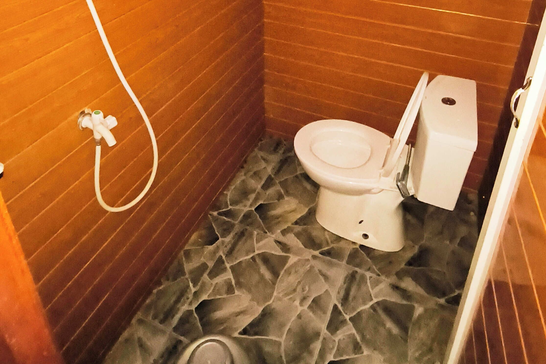 Un baño con inodoro, ducha y piso de baldosas.
