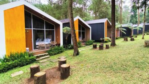 A row of modern, single-story cabins with large windows, surrounded by a well-maintained lawn and trees. - Spekta Merbabu powered by Cocotel (Getasan)