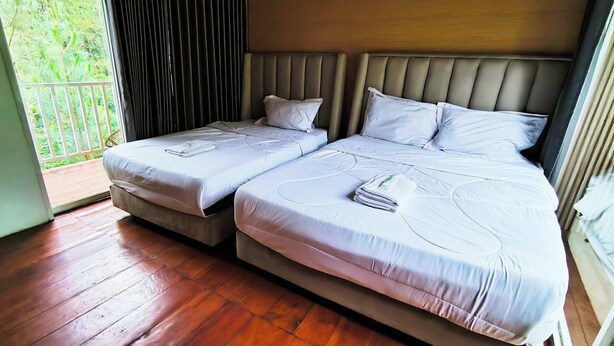 A bedroom with two beds, a wooden floor, and a view of greenery through a window. - Spekta Merbabu powered by Cocotel (Getasan)