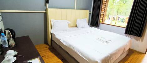 A neatly made bed with white linens, a wooden nightstand with a remote control, and a window with curtains.