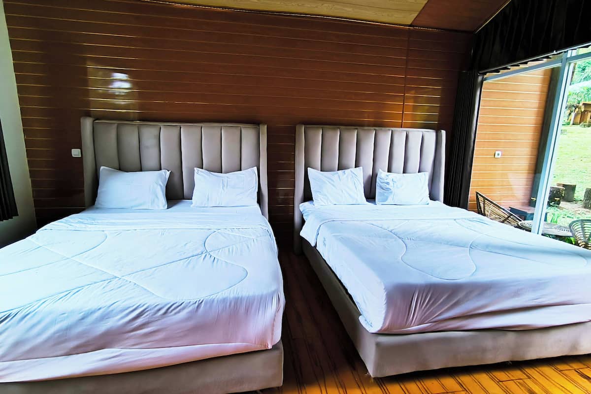 Ein Doppelzimmer mit zwei Betten, Holzvertäfelung an den Wänden und einem großen Fenster mit Blick ins Freie.