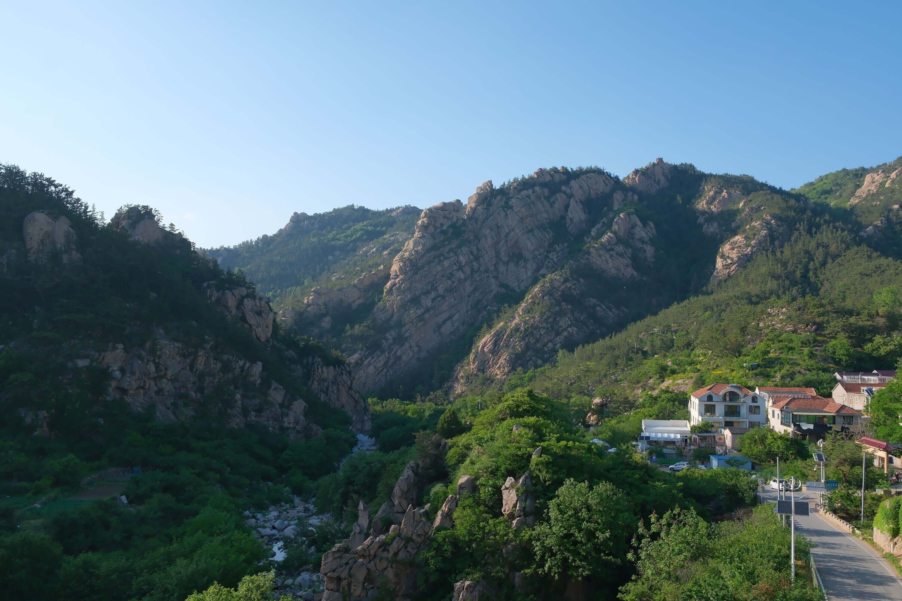 Un paisaje montañoso con una carretera que lleva a un conjunto de edificios.