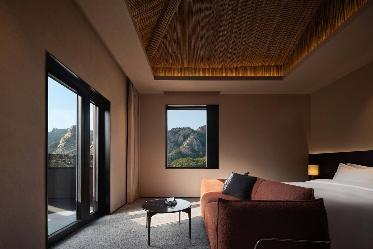 Una habitación de hotel con un ventanal grande, un sofá, una cama y una pequeña mesa.
