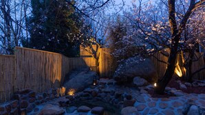 A garden with a stone pathway, large rocks, a wooden fence, and cherry blossoms. - TOPSCAPE Yangshan Hotel (Qingdao)