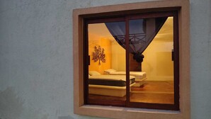 Een kamer met een bed, een klein tafeltje en een kunstwerk aan de muur.