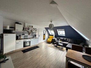Eine moderne Lofts-Wohnung mit Küche, Essbereich und Wohnraum, ausgestattet mit Dachfenstern und einem Schlafplatz in der Galerie.
