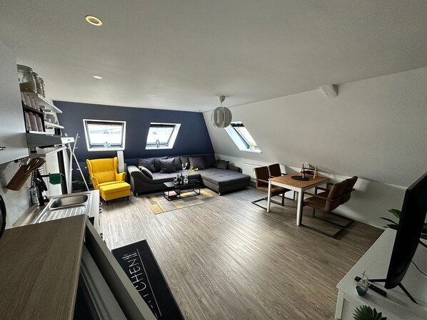 Un appartement moderne de style « loft », comprenant un coin repas, un canapé et une cuisine équipée d’un four encastré.