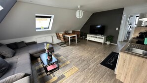 Un salon moderne comprenant un canapé, une table basse, un téléviseur et un coin repas.