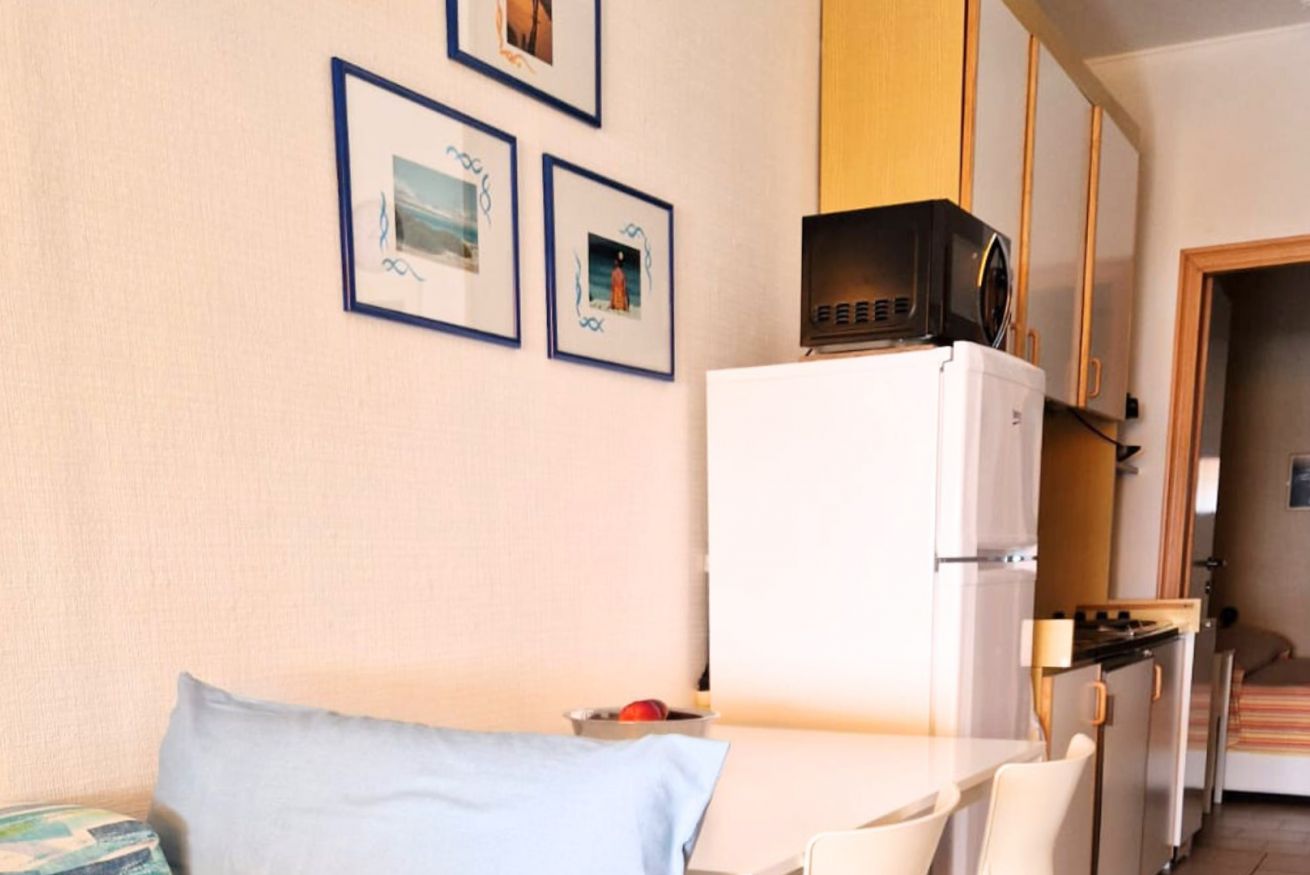 A compact room with a bed, a small kitchenette with a microwave, and framed pictures on the wall.