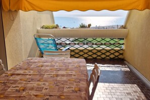 A balcony with a table and chairs, a view of the sea, and a lattice fence.
