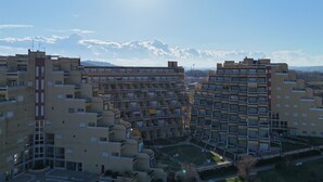 Un edificio residencial alto con varios balcones, un patio central y una vista despejada del paisaje circundante.